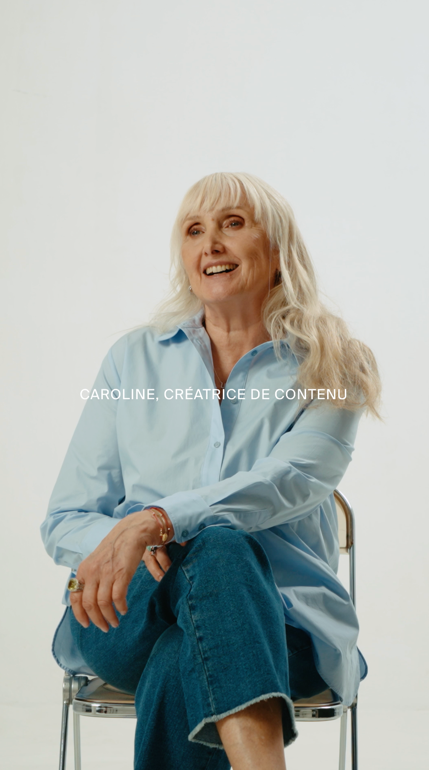 Portrait de Caroline, 65 ans, souriante et lumineuse, incarnant une féminité intemporelle. Elle pose avec assurance, symbole de force tranquille et de sororité, dans l’univers élégant de Devernois.